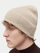 Unisex Organic Cashmere Rib Knit Beanie Warm Grey worn by model, detail view on white background #color_dusty-beige
