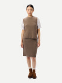 Woman wearing a brown knitted outfit with a white shirt underneath on a white background.  #color_taupe