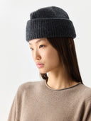 Woman wearing a dark gray knit beanie on a light gray background #color_charcoal