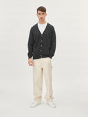 A man wearing a gray V-neck cashmere cardigan with a round neckline and front button details. #color_charcoal