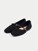 Pair of black flat shoes with a strap on a light gray background #color_black