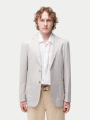 Man wearing a light gray blazer over a white shirt with beige pants on a white background. #color_light-taupe