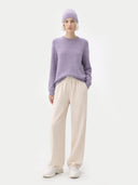 Person wearing a light purple jumper and beige pants on a white background #color_ash-purple #ai-image