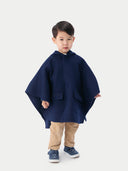 A child wearing a navy hooded cashmere poncho with a plain background. #color_navy-blue