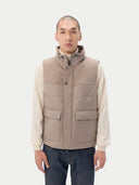 A sleeveless beige cashmere vest with a high collar, front zipper, and two large front flap pockets, shown flat against a light gray background. #color_taupe
