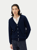 Man wearing a navy cardigan over a white shirt on a light gray background. #color_navy-blue