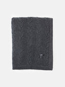 Dark gray knitted blanket with a brand logo on a white background. #color_charcoal