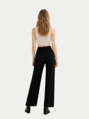 back view of a woman wearing a beige top and black pants on a white background #color_off-white #ai-image
