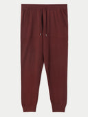 A pair of dark burgundy cashmere jogger sweatpants with an elastic waistband, drawstring, and side pockets, shown flat against a light gray background. #color_dusty-plum