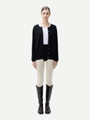 Person wearing a black cardigan over a white shirt with beige pants on a light gray background #color_black