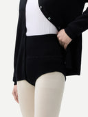 Person wearing a black cardigan over a white shirt with beige pants on a light gray background #color_black