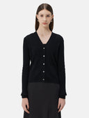 A woman wearing a black lightweight cashmere cardigan with long sleeves and a V-neck collar, paired with a dark skirt.
#color_black