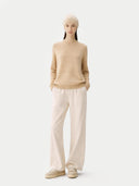 Person wearing a beige jumper and white pants on a white background #color_beige #ai-image