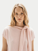 close up of a woman wearing a light pink dress with a scarf tie against a plain background #color_light-blush #ai-image