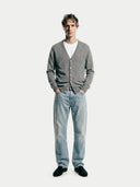 front view of a man wearing a gray v-neck cardigan, white shirt, and blue jeans on a white background #color_dim-gray #ai-image