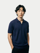 Man wearing a navy blue cashmere polo shirt against a plain background. #color_iris-navy #ai-image