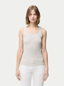 A woman wearing a beige lightweight cashmere silk tank top with no visible pattern or print, paired with white trousers. #color_pure-white