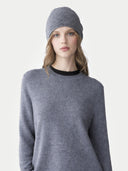 Woman wearing a grey jumper and matching beanie on a light grey background #color_steel-gray #ai-image