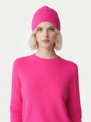 Person wearing a bright pink beanie and jumper on a light grey background. #color_magenta-pink #ai-image