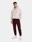 A pair of dark burgundy cashmere jogger sweatpants with an elastic waistband, drawstring, and side pockets, shown flat against a light gray background. #color_dusty-plum #ai-image