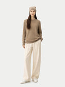 Person wearing a brown sweater, beige beanie, and white pants on a white background. #color_taupe #ai-image