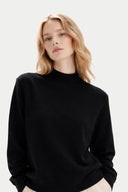 Woman wearing a black sweater against a plain background Gobi Cashmere #color_black #ai-image