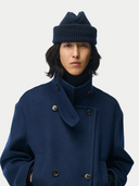 Person wearing a blue coat and matching beanie on a white background #color_navy