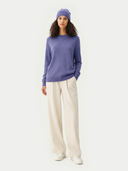 Woman wearing a purple sweater and white pants on a white background #color_dusted-peri #ai-image