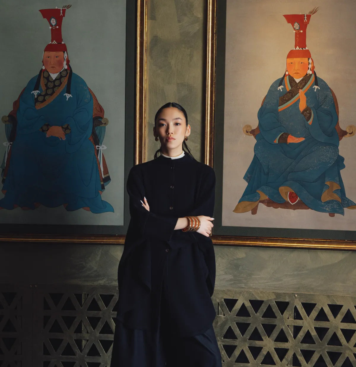 Woman in a black cashmere outfit standing between two Mongolian traditional portrait paintings | GOBI Cashmere